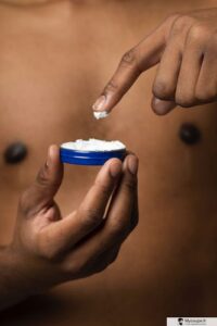 homme qui met le doigt dans une crème visage a l'acide hyaluronique